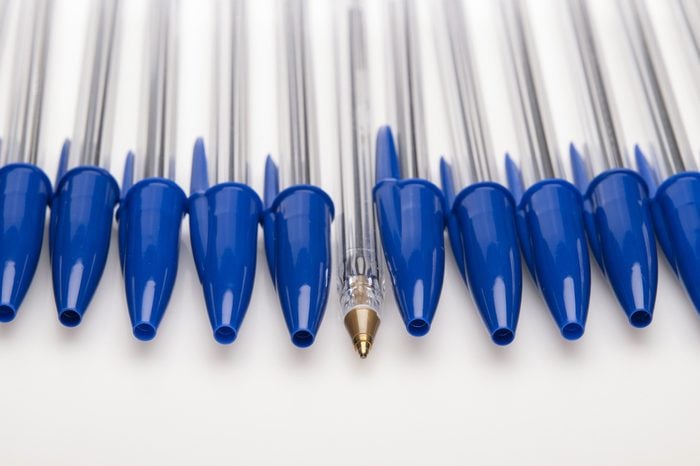 Blue ballpoint pens capped with one uncapped on white background