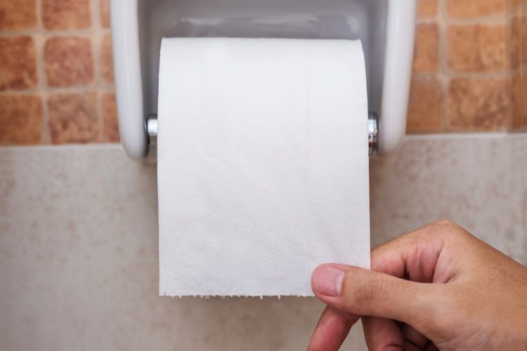 Close-up roll toilet paper in restroom with hand pulling