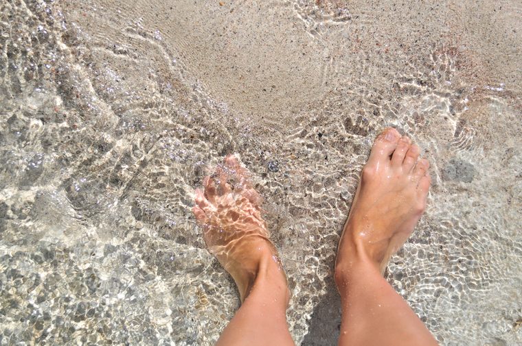 Feet in the water on the sand. Mediterranean sea, the island of Crete. Greece.