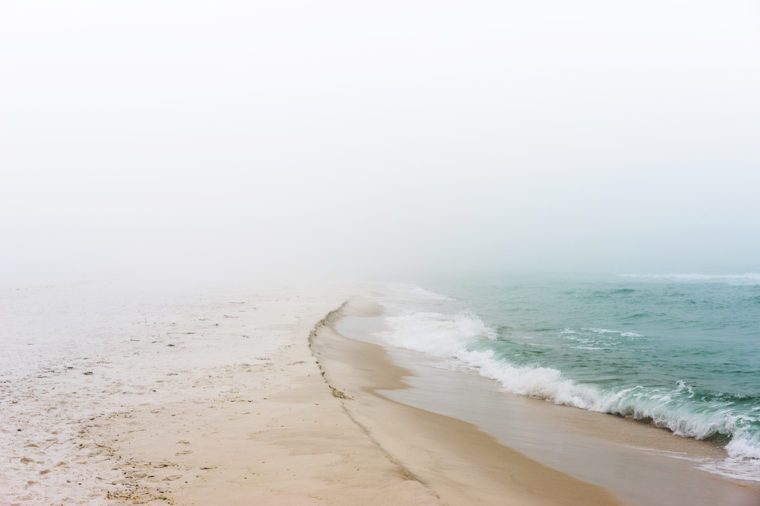 Soft pastel landscape photo of waves breaking on a pristine, peaceful, unpopulated beach.