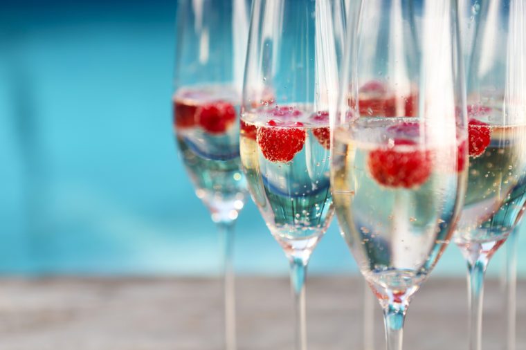 Champagne glasses with raspberry. Summer pool party