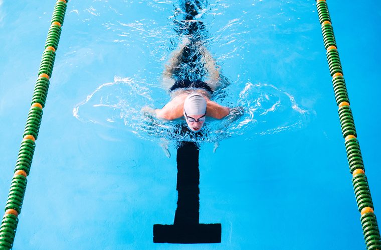 Senior man swimming in an indoor swimming pool.