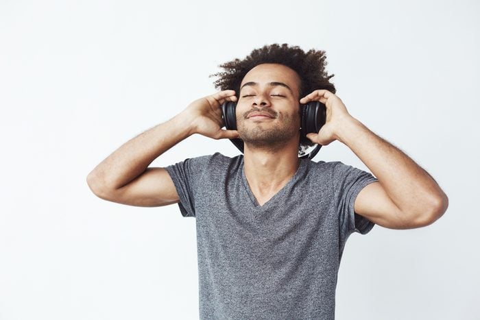 Happy african man smiling listening to music in headphones. Closed eyes.