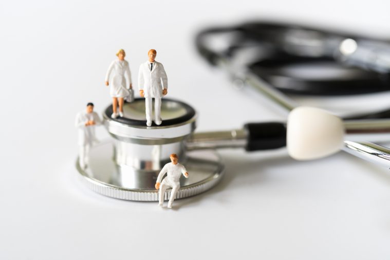 Miniature people, Doctor and Nurse emergency medical team on stethoscope on white background. Health care, life insurance travel hospitality concept.