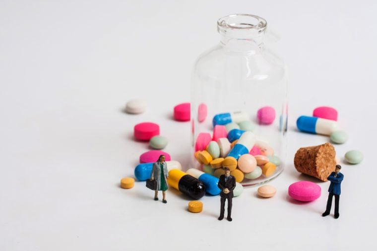selective focus photo of miniature business man with casual spilled from pill bottle on white background, abstract background to medical concept
