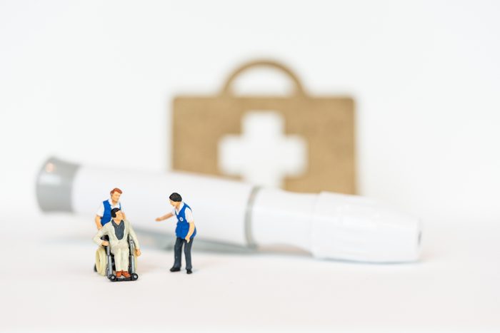 Miniature people, patient in wheel chair and blood glucose meter, lancet.Healthcare medical and check up, diabetes, glycemia, and people concept.