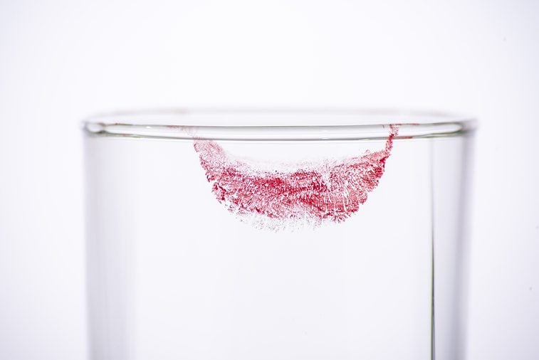 Closeup lipstick on empty glass from woman drink on white background