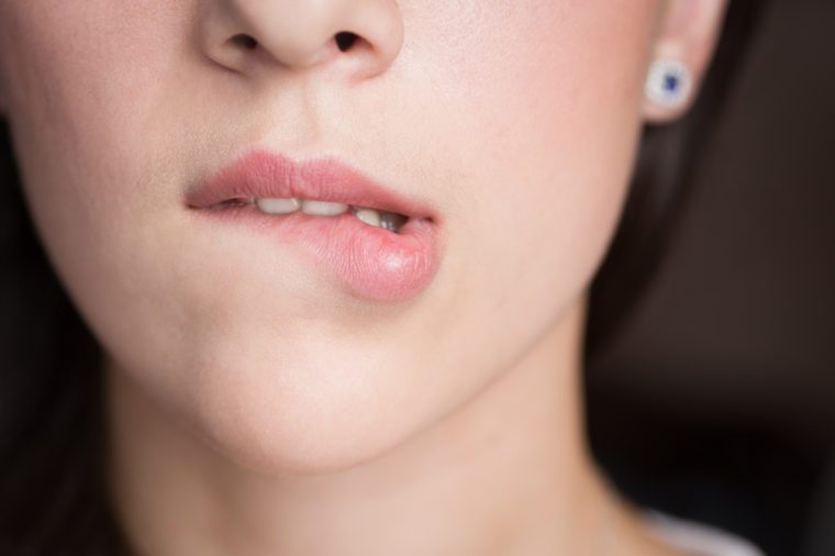 Young woman bites her lips closeup.