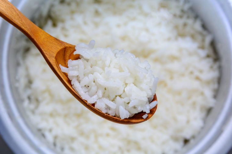 Cooked rice in pot with wood spoon