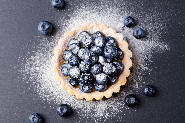 Blueberry tartlet, pie, tart with vanilla custard. Slate stone background. Top view Copy space
