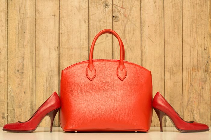 Woman accessories on wood background, red handbag and stileto