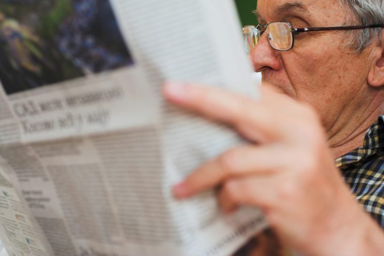 Caucasian older businessman reading newspaper