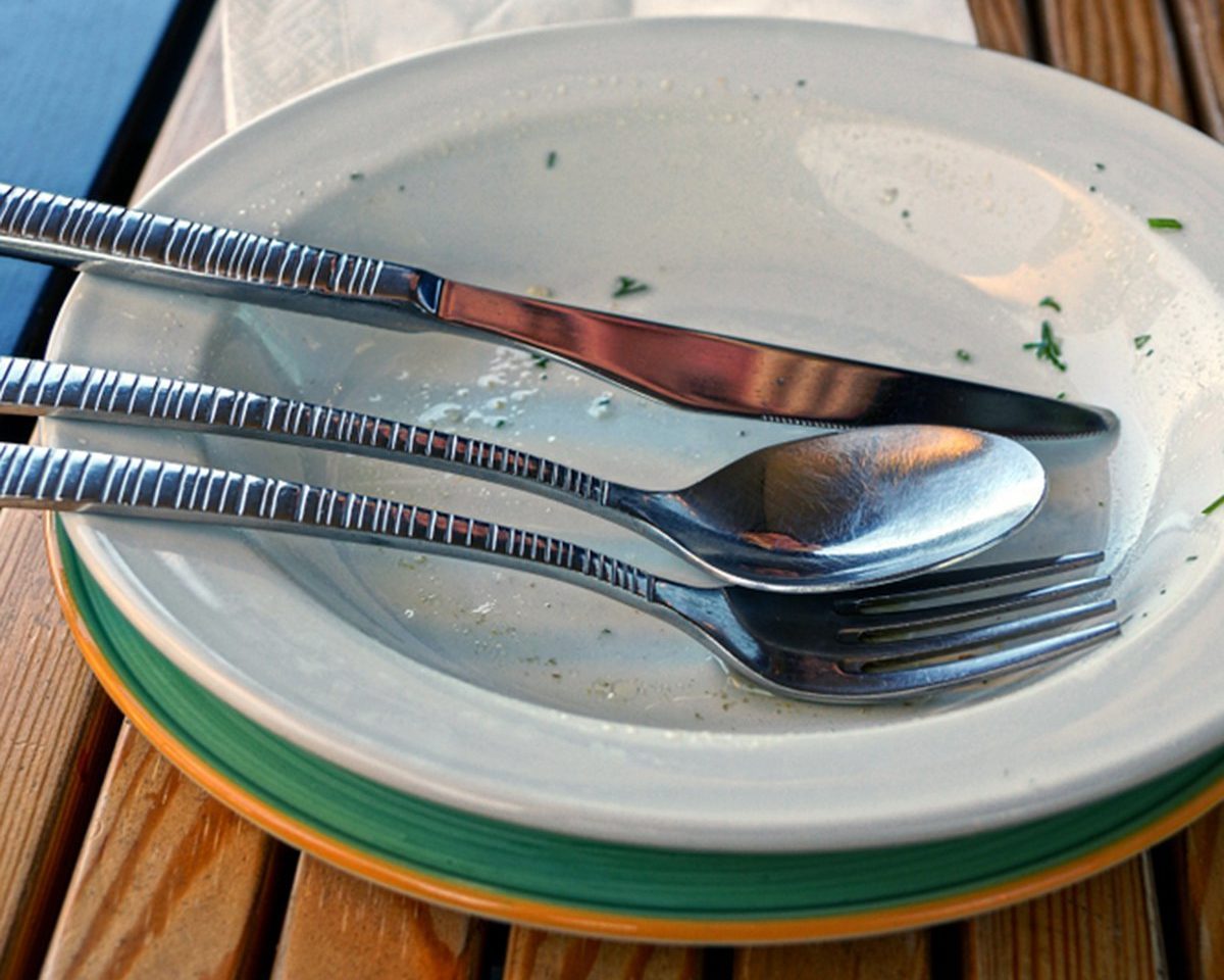 Dirty dishes with cutlery on a brown wooden table