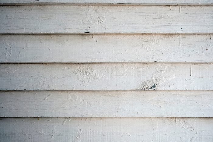 Old wooden siding painted in white. White old siding background.