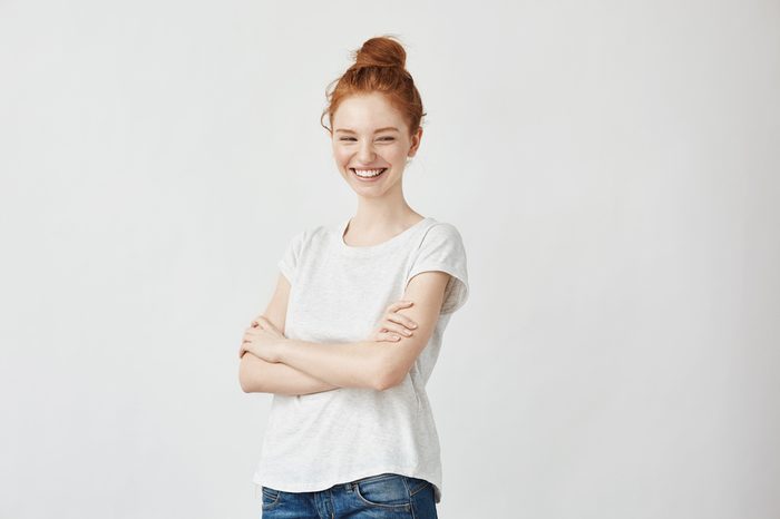 Portrait of happy young beautiful ginger girl laughing. Off camera. Copy space. Isolated on white.