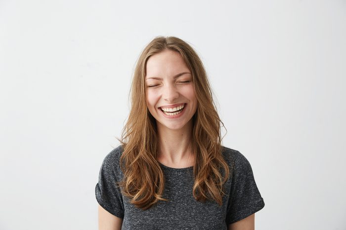 Young cheerful happy girl smiling laughing with closed eyes over white background.