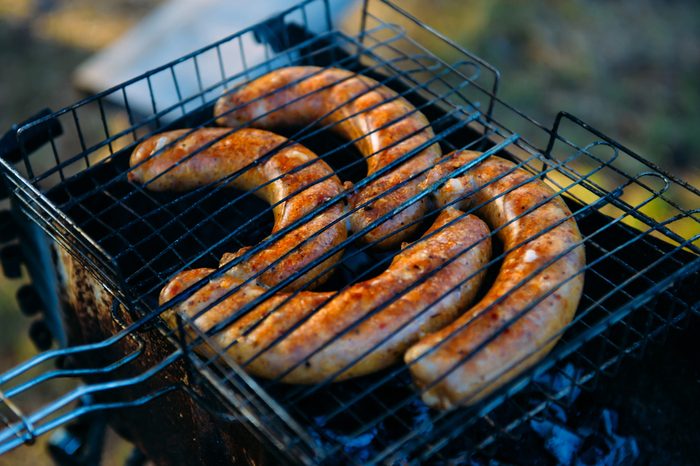 Natural shot of grilling sausages on barbecue grill. BBQ in the garden