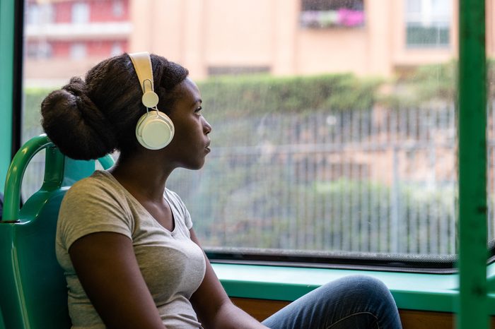 Young black woman listening music travelling by bus looking outdoor the window, pensive - thoughtful, thinking future, music concept