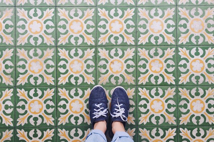 Top view selfie of feet in sneaker shoes on vintage art pattern floor with copy space
