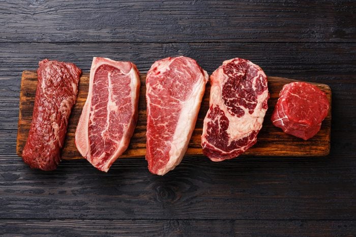 Variety of Raw Black Angus Prime meat steaks Machete, Blade on bone, Striploin, Rib eye, Tenderloin fillet mignon on wooden board copy space