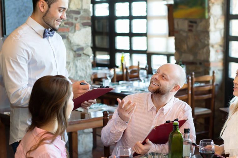 Relaxed adults people having dinner and respectful waiter