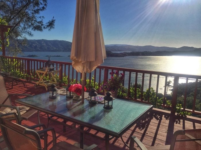 A romantic outdoor patio dining table and chairs with an umbrella overlooks beautiful Clearlake in Lake County California