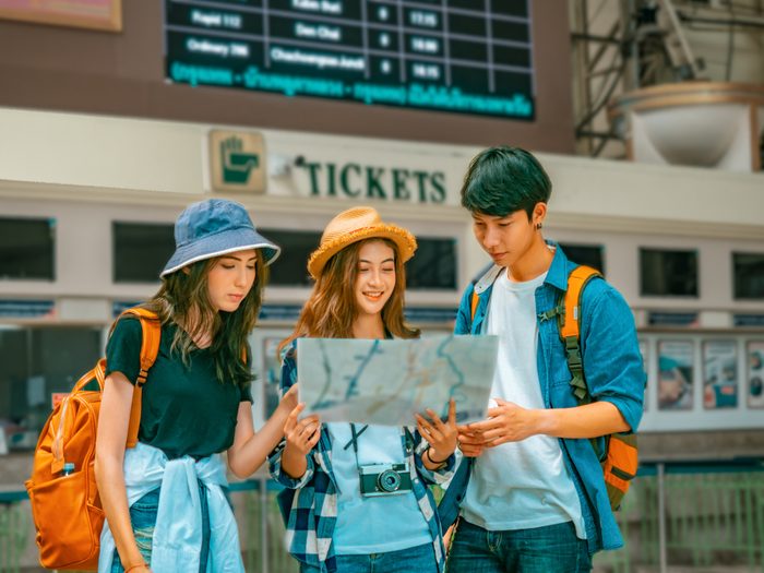 travel concept.group of traveller friend with trikets counter and time table background.asia tourist looking map in terminal at Hualumpong Bangkok train station.