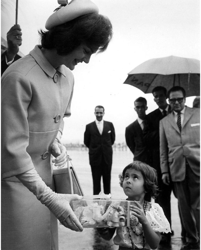 Arrival ceremony at Maiquetia Airport, Caracas, Venezuela. First Lady Jacqueline Kennedy accepts corsage from young Venezuelan.