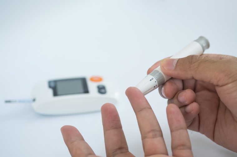 Close up of asian man's hands using lancet on finger to check blood sugar level by glucose meter, Healthcare medical and check up, diabetes, glycemia, and people concept