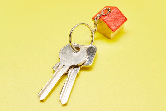 set of keys with house shaped keychain on yellow background