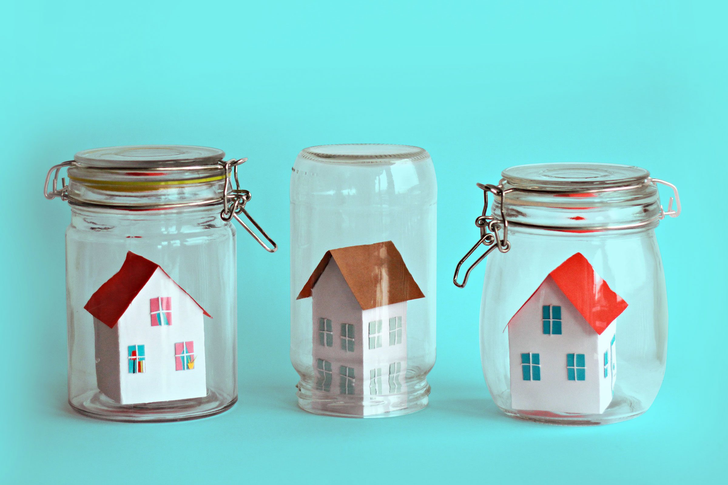 three houses in glass jars on teal background
