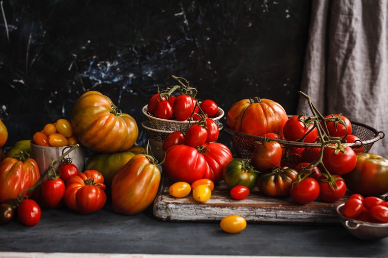 Heirloom variety tomatoes on dark rustic table text abundance ripe tomatoes