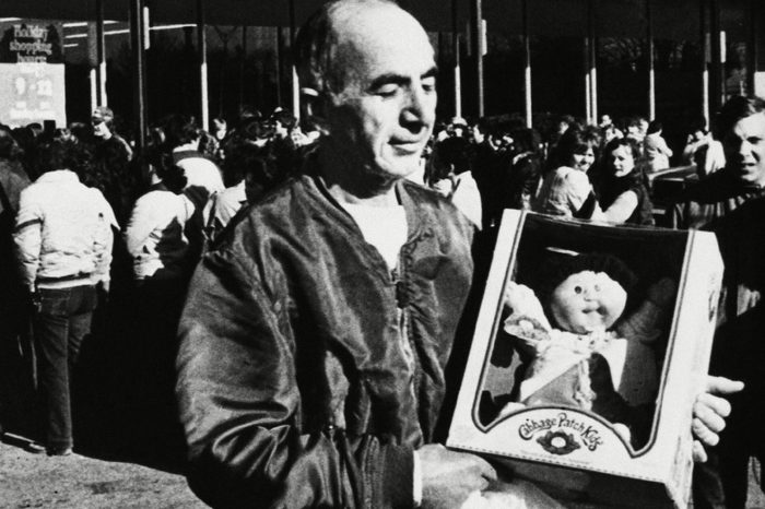 A happy customer displays his newly purchased "Cabbage Patch Kid" doll on as he leaves a south Bellingham, Mass. storefront crowded with people hoping to make similar, purchases. The moon faced cloth dolls, made by Coleco, have created quite a stir among shoppers nation wide, with some people waiting in 5-hour lines to buy them