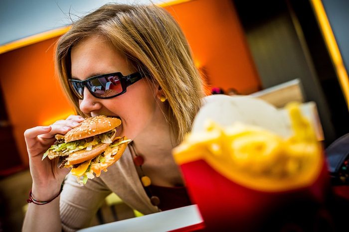 BUDAPEST, HUNGARY, April, 2013: Young woman eating a Big Mac hamburger menu in a McDonald's restaurant. Illustrative editorial.
