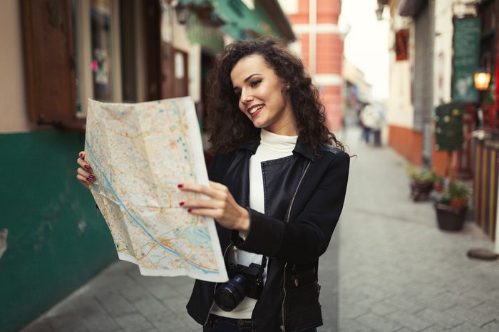 Female tourist exploring city while holding map