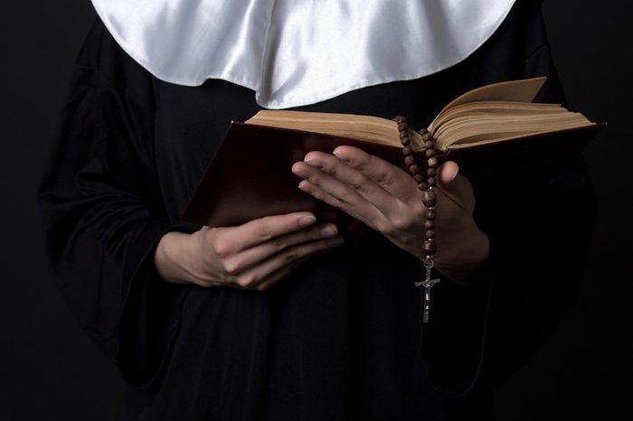 nun hands holding bible book over grey background