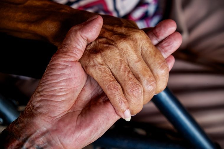 The old man's hand touching the hand of a sick old woman 