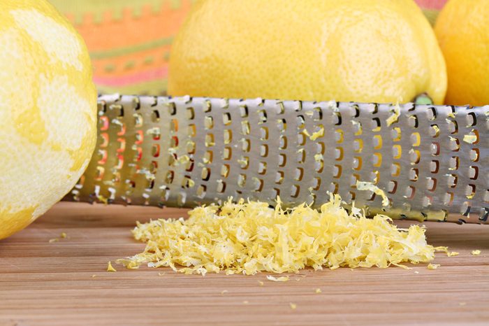 Lemon zest with zester behind zest. Macro with selective focus on lemon zest.