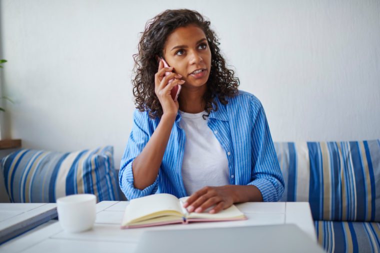 Serious african american woman having consultancy with service operator talking on mobile phone on free time,pensive dark skinned student banking through telephone conversation sitting in cafe