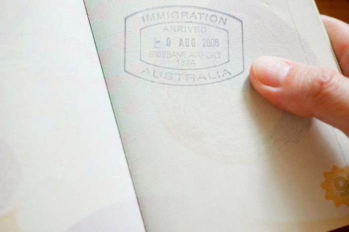 Hand holding passport with Australian immigration stamp for entering the country