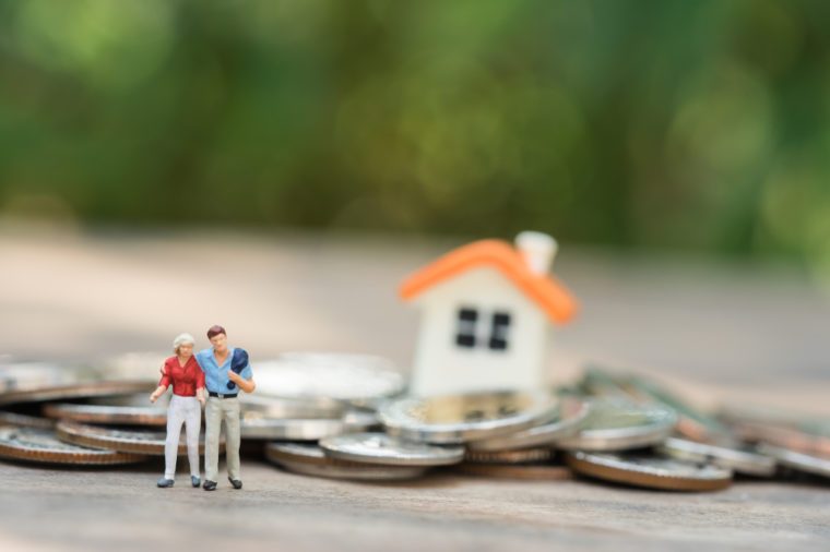 Miniature people: family standing on coins stacks with house model on the top stack. concepts. Concept for property ladder, mortgage,real estate investment, money, love and Valentine's day.