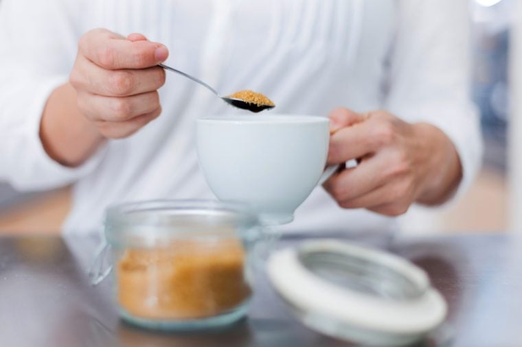 Woman hands serving sugar on coffee cup