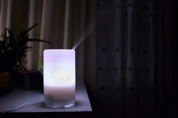 Essential oil diffuser producing mist while glowing in the dark