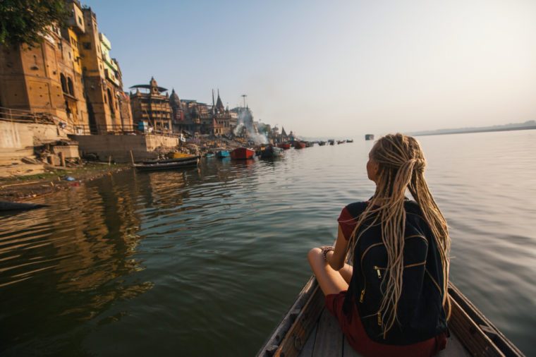 Woman traveler on a boat glides through the water on the Ganges river of Varanasi, India.