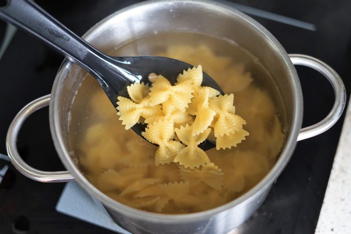 putting pasta farfalle in boiling water. spoon.