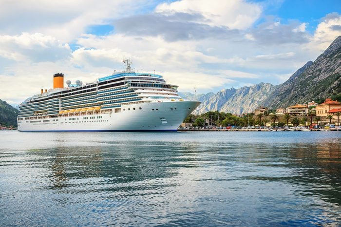 Big cruise ship in the port at the ancient city Kotor surrounded by mountains, Adriatic sea, Montenegro, Mediterranean summer landscape.