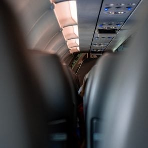 View of the roof and seats at an airplane with the lights on