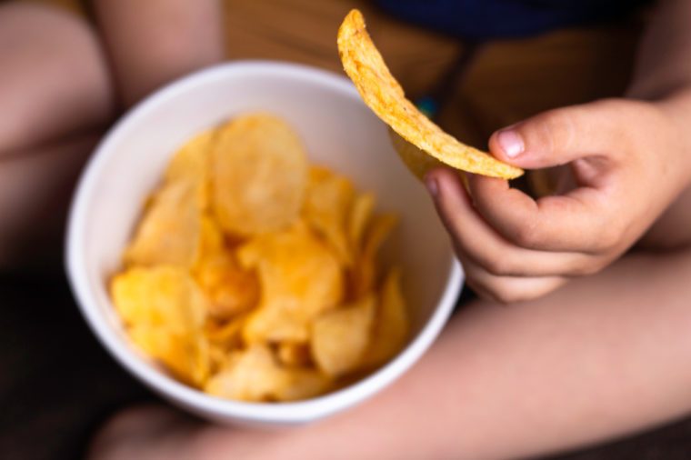 child's hand holds potato chips, concept of harmful food, fast food, obesity
