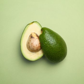 Cut avocado on color background, top view