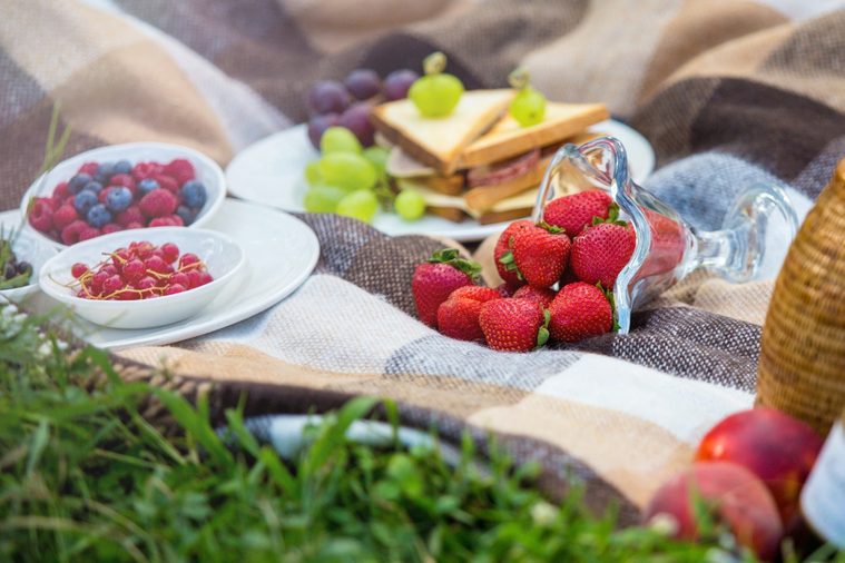 summer picnic - fresh strawberries, berries, sandwiches on a plaid